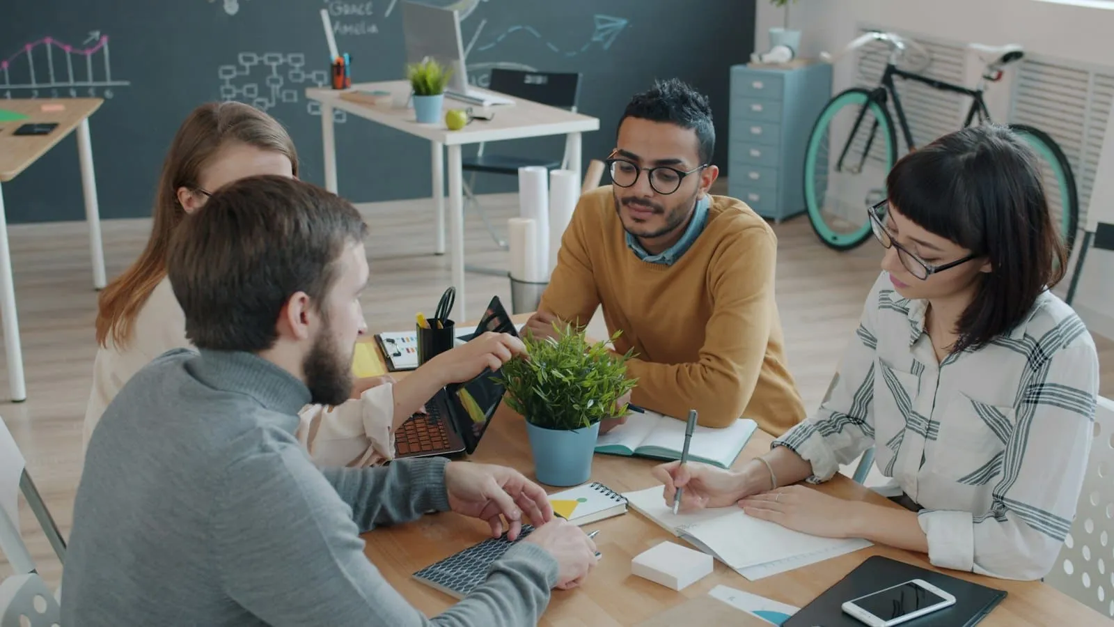 Un equipo de proyecto planifica en la mesa con portátil y notas
